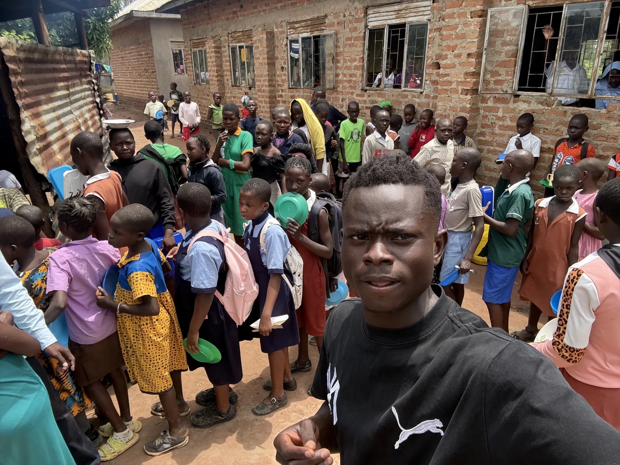 A Clon Circus Uganda coach joins children during a community meal support activity.